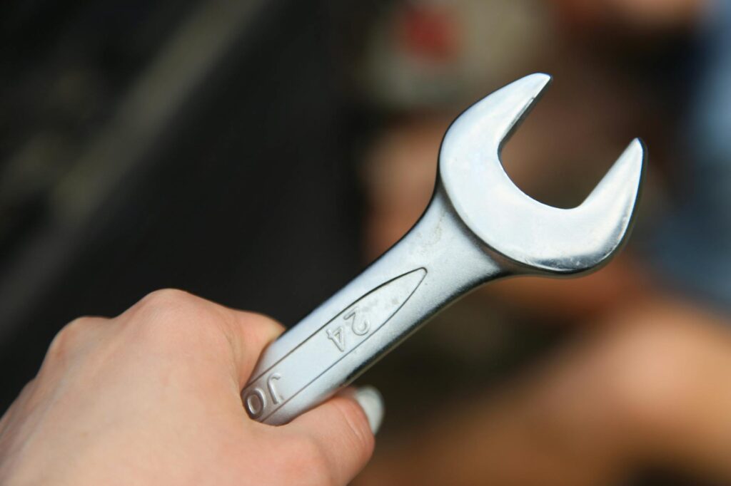 close up of a hand holding a metal wrench